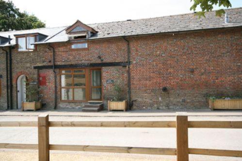 ein Backsteingebäude mit einem Zaun davor in der Unterkunft The Old Stables in Leighton Buzzard