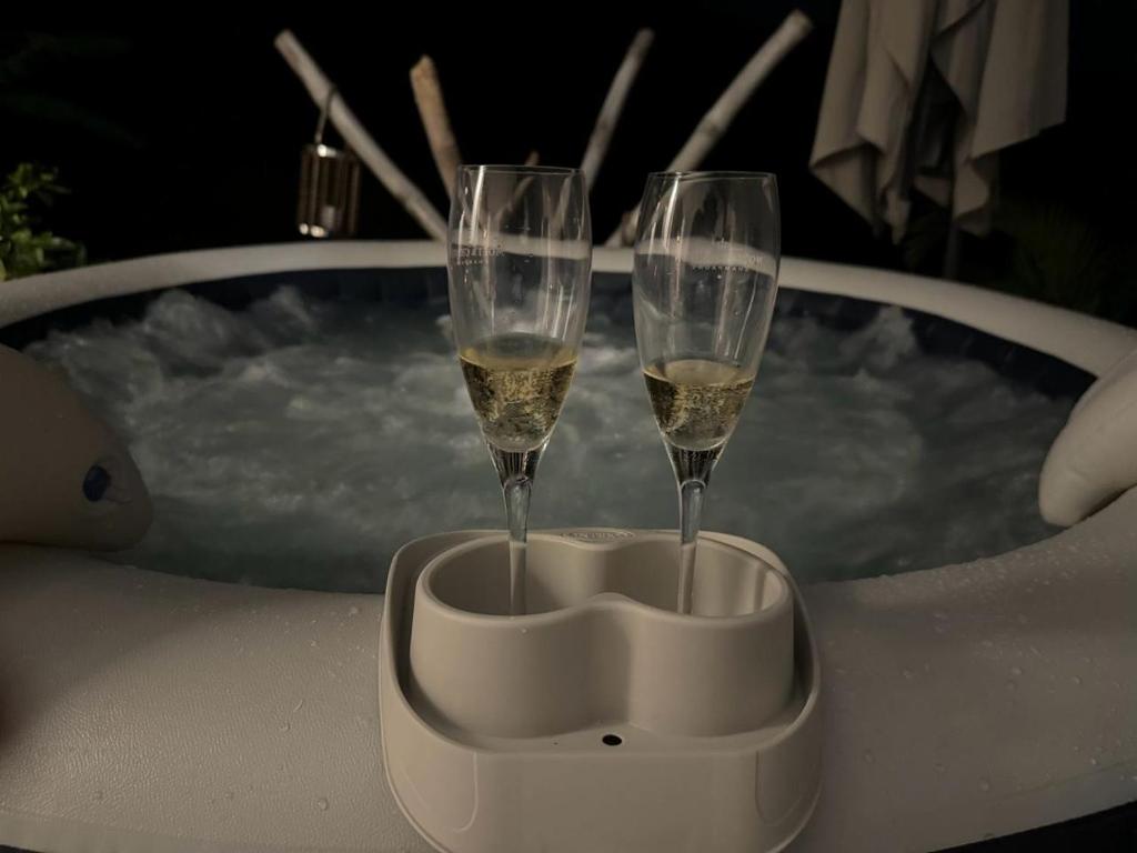 dos copas de champán sentadas en una mesa frente a una bañera de hidromasaje en Le Clos de Bourgueil, en Sainte-Anne