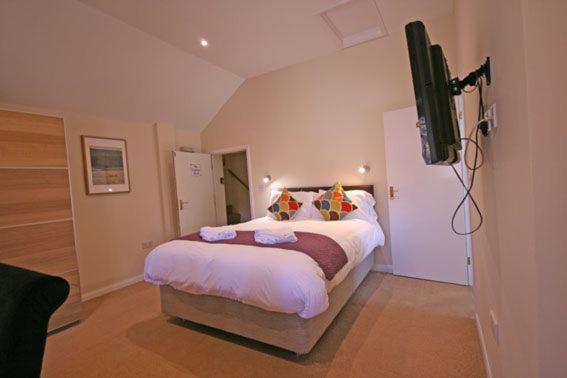 a bedroom with a bed and a flat screen tv at The Elephant Room in Ivinghoe