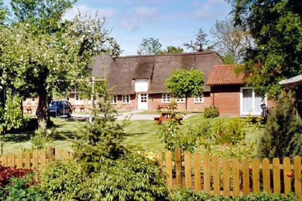 una casa con una valla delante de ella en Friesisches Reetdachferienhaus, en Bordelum
