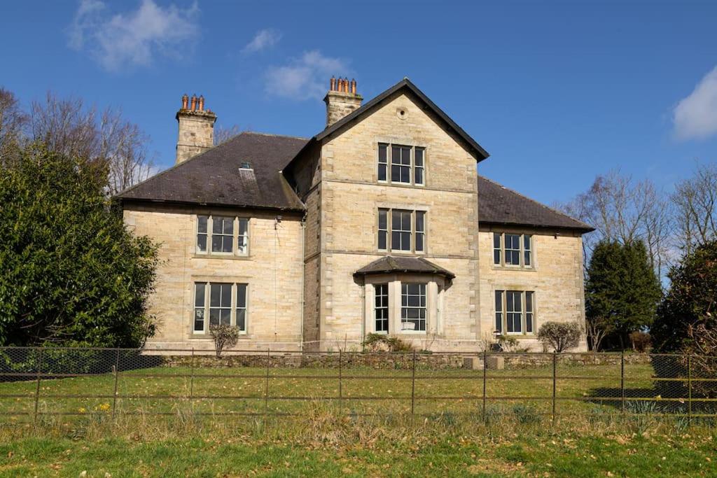 a large stone house with two chimneys at Magnificent Period Country House in Rothley