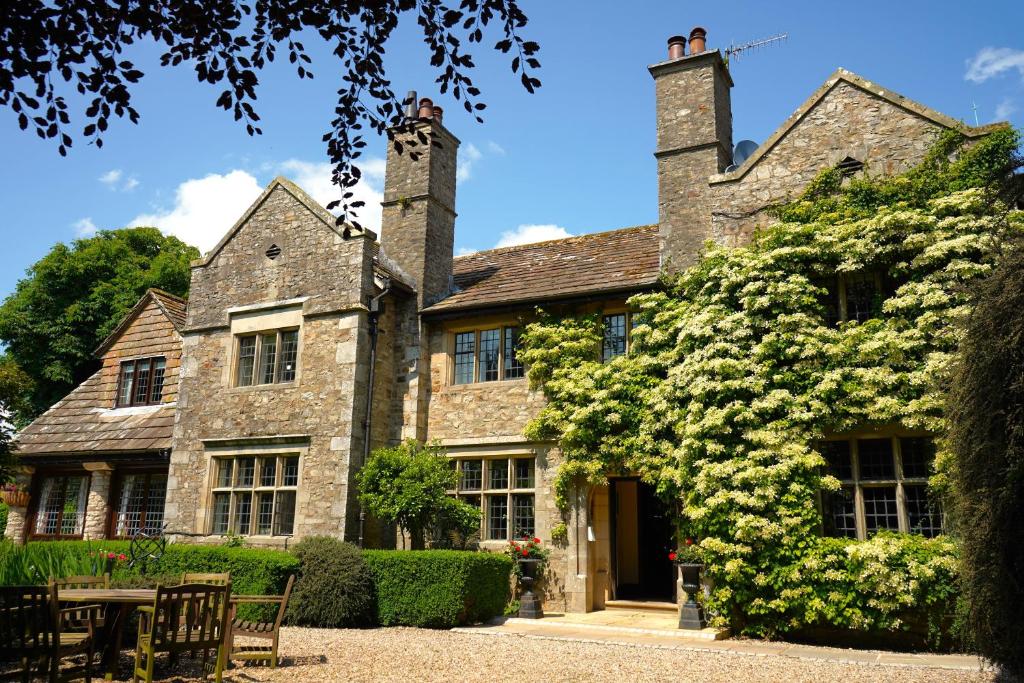 an old stone house with a large flowering bush at Stone House Hotel in Hawes