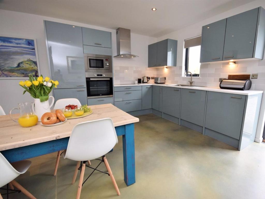 a kitchen with blue cabinets and a wooden table at Sienna Cottage in Bradworthy