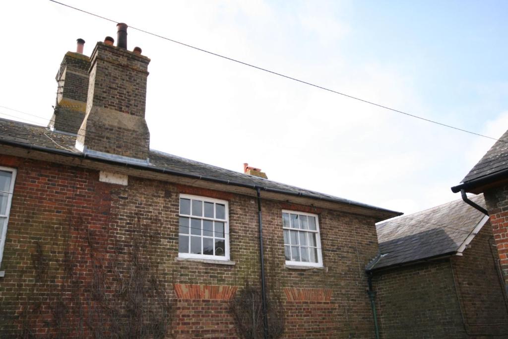 a brick building with two windows and a chimney at Beacon View in Ivinghoe