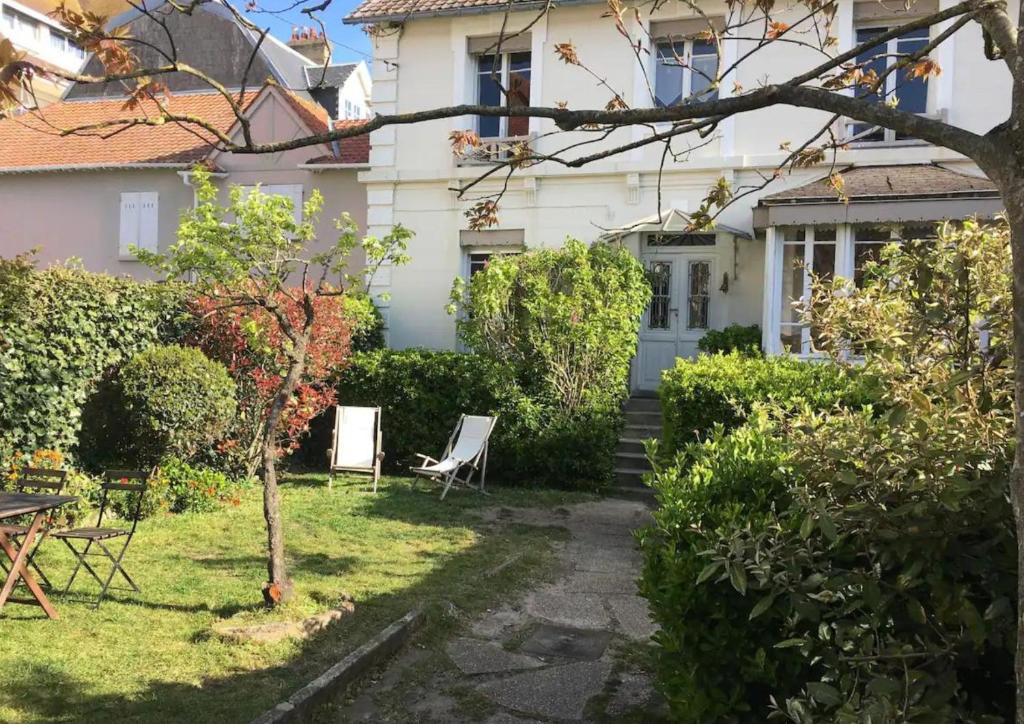 una casa blanca con una silla en el patio en Lofoten, en Le Touquet-Paris-Plage