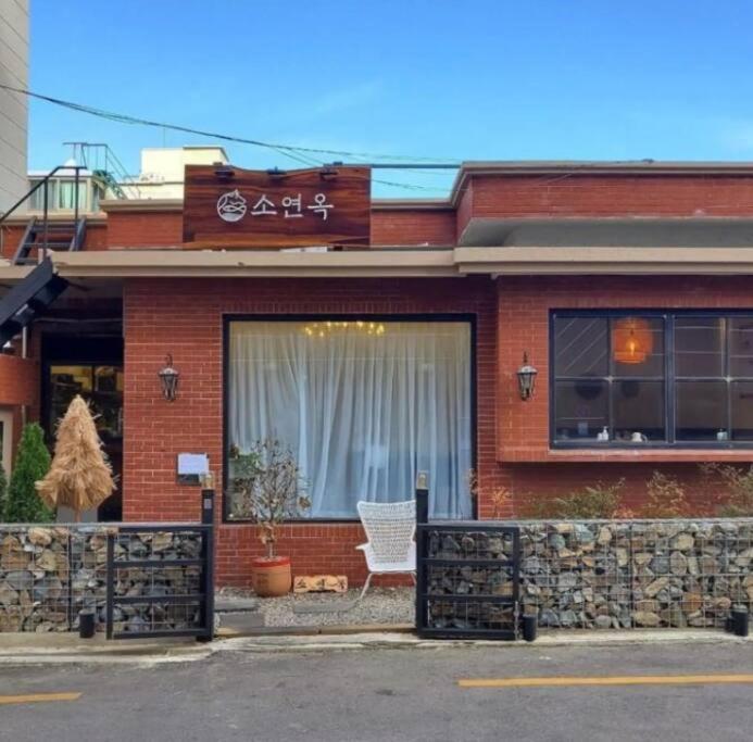 a red brick building with a white chair in the window at Chille with free parking #Jeonpo station 2min #new #cozy #jazzbar #laundary everyday #healing in Busan