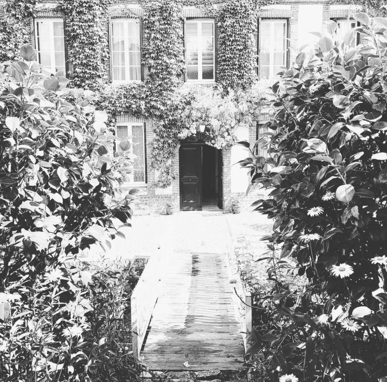 une photo en noir et blanc d'un bâtiment avec une porte dans l'établissement Aux bonheurs des roses, à Valmont