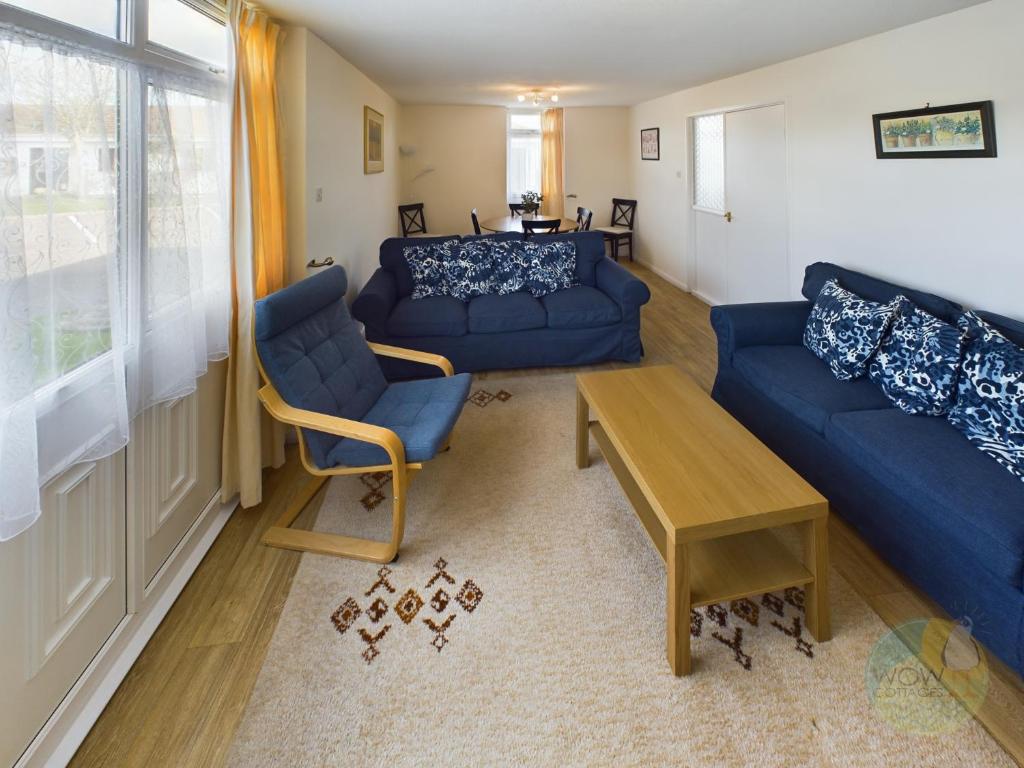 a living room with blue couches and a table at Lovely Chalet - Welcome Holiday Park Dawlish warren in Bellaghy