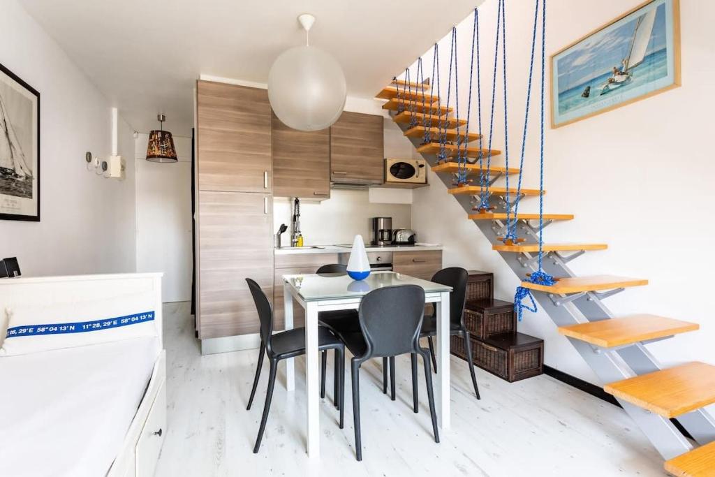 a dining room with a table and chairs and a staircase at Le Capucin - Petit duplex avec place de parking in Dinard