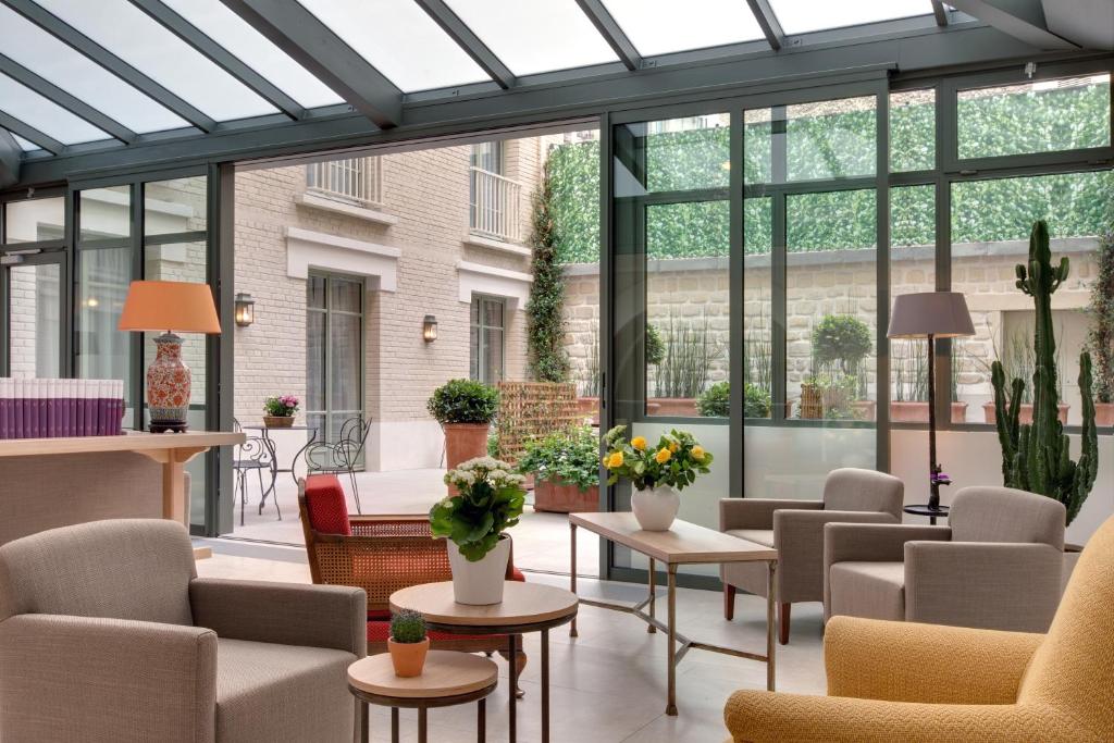 a conservatory with chairs and tables and windows at Le Littré in Paris