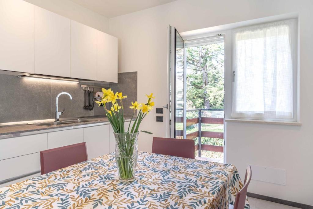 a vase with yellow flowers on a table in a kitchen at La Casa Azzurra, Levico Terme Ospitar in Levico Terme