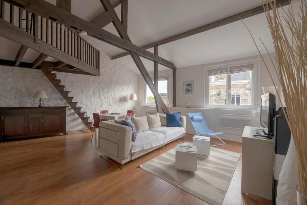 uma sala de estar com um sofá branco e uma escada em L'Ancrage - Beau duplex 2 chambres - Plage à 5 min em Dinard