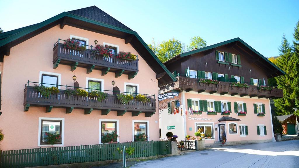 ein großes rosafarbenes Gebäude mit Balkonen und Pflanzen in der Unterkunft Hotel-Pension Falkensteiner in Sankt Gilgen