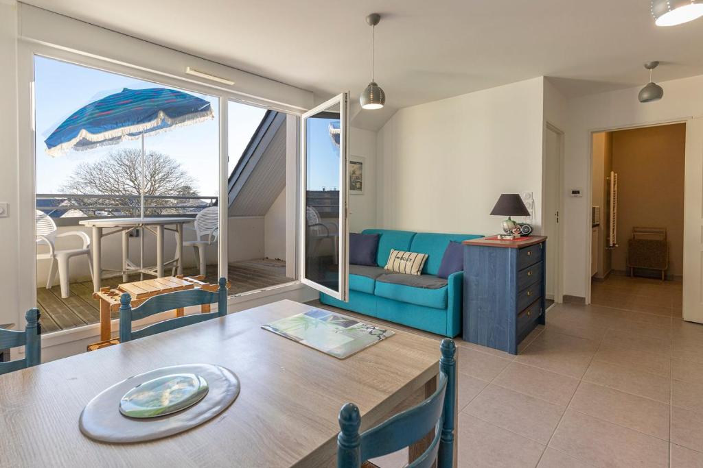 Les Oyats - Appartement 1 chambre - Balcon في سان كولوم: غرفة معيشة مع أريكة زرقاء وطاولة