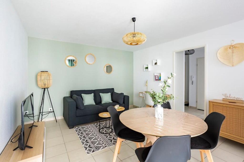 uma sala de estar com uma mesa e um sofá em Le Sévigné - Cosy et calme - balcon et parking em Cesson-Sévigné