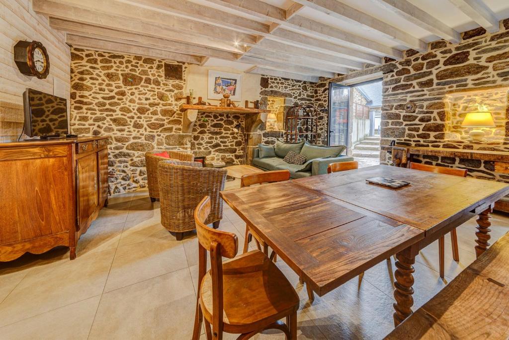 jadalnia z drewnianym stołem i kamienną ścianą w obiekcie Minihic - Belle maison 3 chambres- Proche Mer w Saint-Malo
