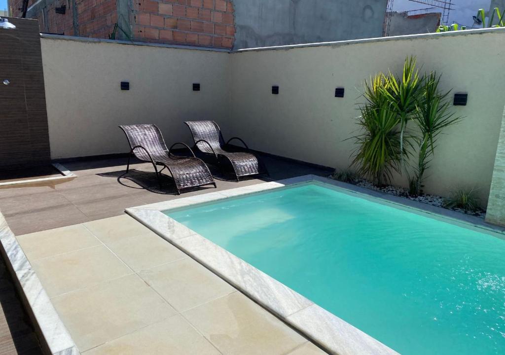 2 chaises et une piscine sur une terrasse dans l'établissement Casa temporada Arembepe Ba, à Camaçari