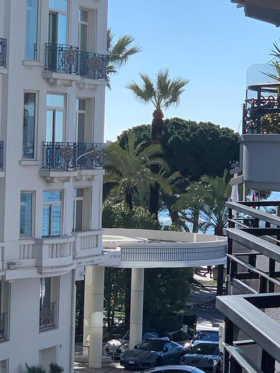 un bâtiment blanc avec des voitures garées dans un parking dans l'établissement My Ty Croisette Martinez YourHostHelper, à Cannes