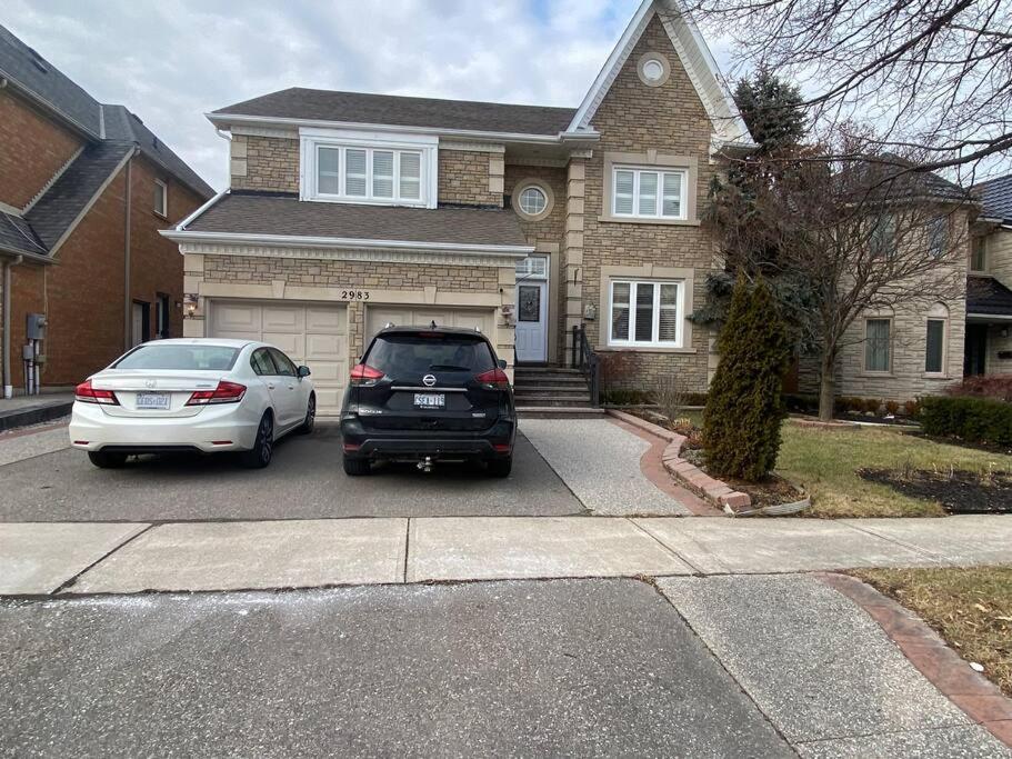 two cars parked in a parking lot in front of a house at 4 Bedroom House in Mississauga in Mississauga