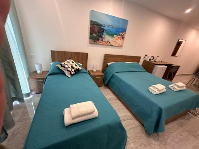 two beds in a room with green sheets and towels at La Bella Guesthouse in St. Julianʼs