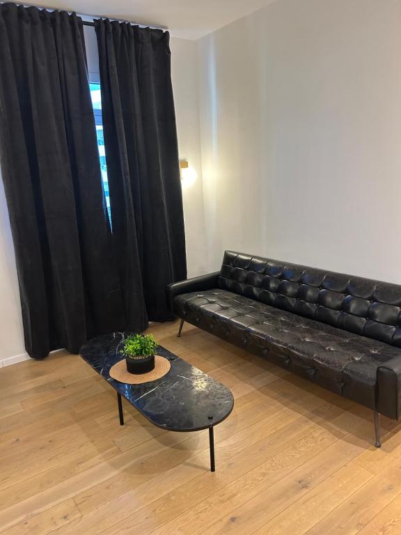 a living room with a black leather couch and a table at Sima suite 3 in Ashdod