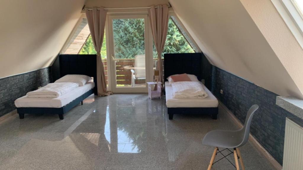 Cette chambre mansardée comprend deux lits et une chaise. dans l'établissement Zimmer in Wohnung, Monteure, Zentral,, à Enger