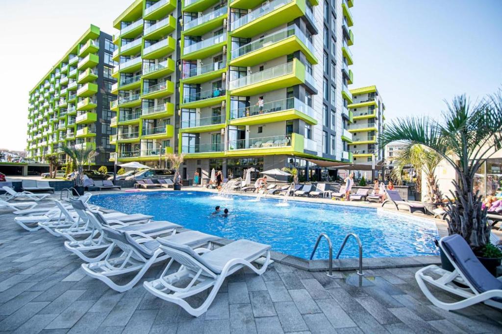 une piscine avec des chaises longues et un bâtiment dans l'établissement Apartament Katrina - Alezzi Beach - Sea View, à Mamaia Nord – Năvodari