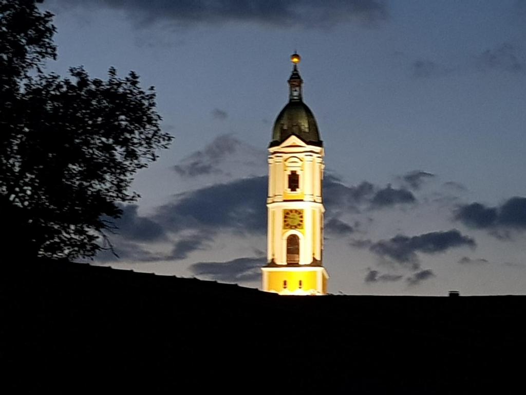 a clock tower lit up at night with a sky at Ehemalige Schmiede -Dormitorium- in Ochsenhausen