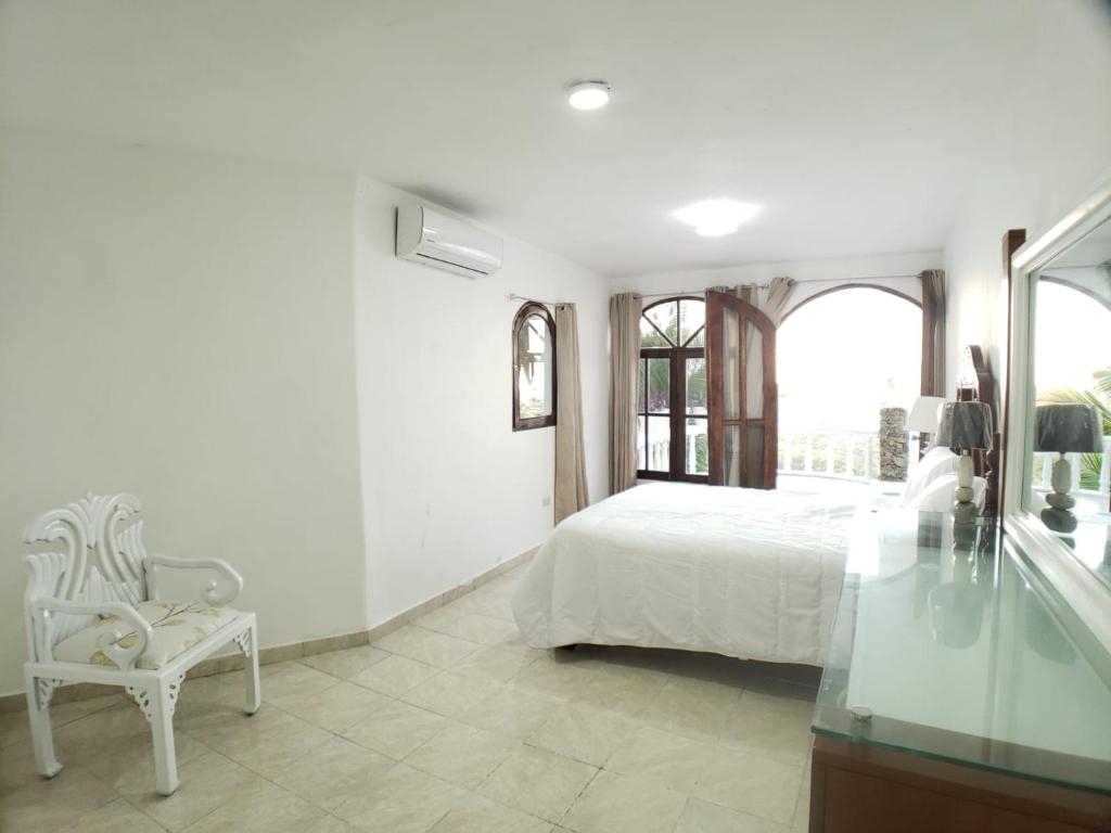 a white bedroom with a bed and a chair at Immaculate 1-Bed Apartment in Cofresi in Las Flores