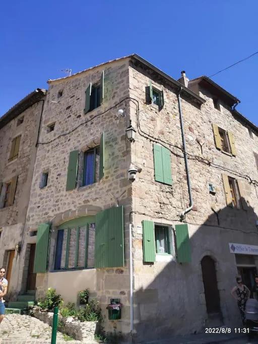 - un vieux bâtiment en pierre avec des volets verts dans l'établissement Gites Terre et Ciel, à Largentière