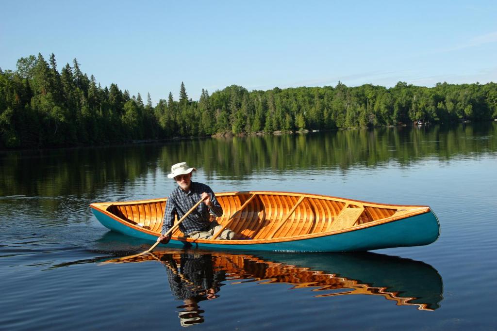 Un hombre está remando en un barco en un lago en Riverfront Cottage Canoe Included & Playroom Fun, en Wasaga Beach