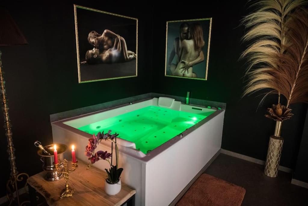 ein Badezimmer mit einer grünen Badewanne mit einem Tisch und Kerzen in der Unterkunft La Rose Médiévale Balnéo & Sauna in Domfront