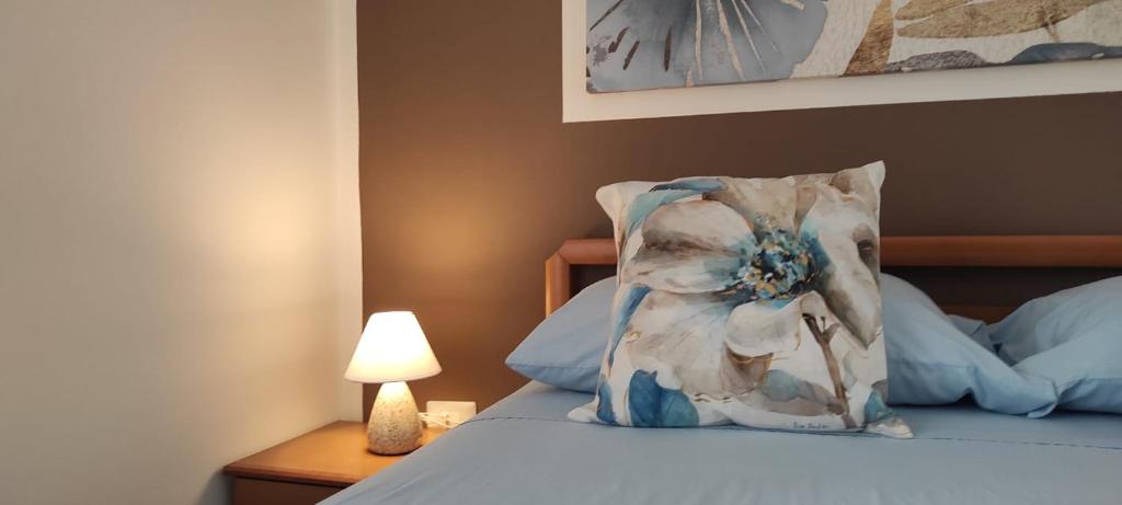 Dormitorio con cama con almohada y lámpara en La Dormidera, en Alghero