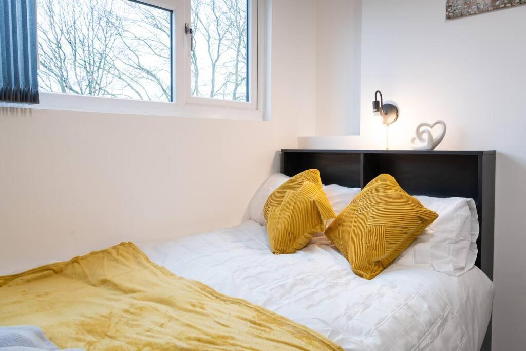 łóżko z dwoma żółtymi poduszkami na górze w obiekcie Sleek and Stylish Studio: Old Trafford w Manchesterze