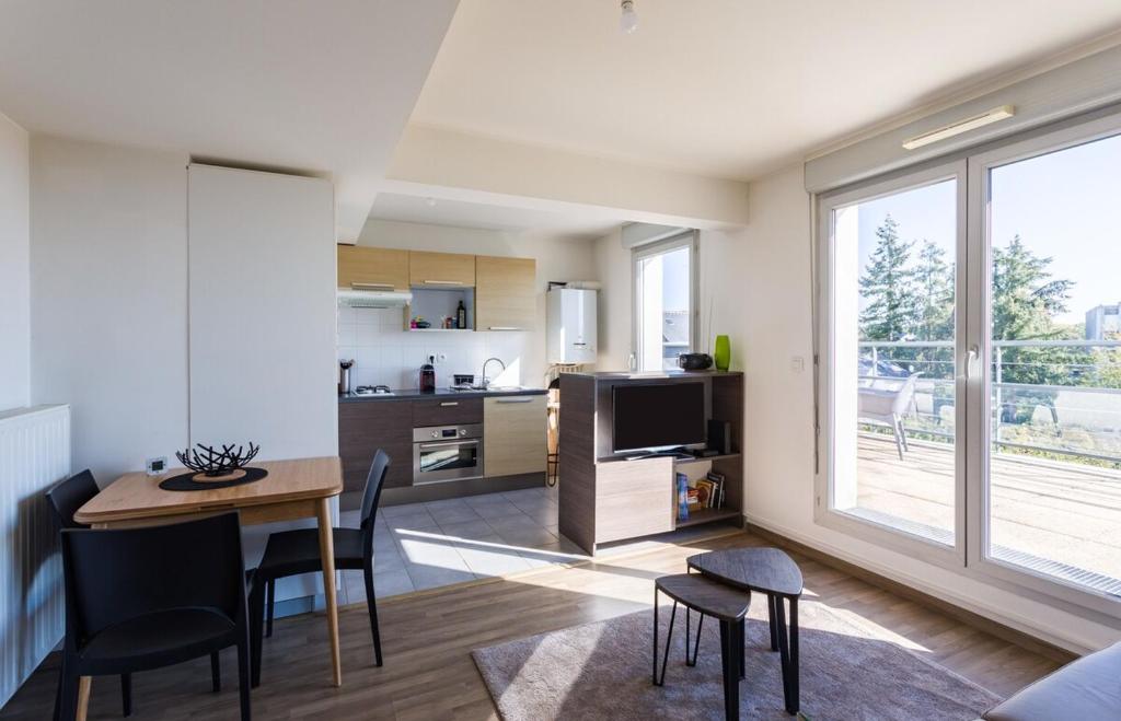 a kitchen and living room with a table and chairs at La Rossa proche métro parking privé in Rennes