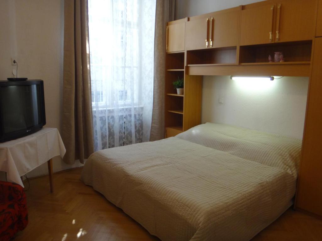 1 dormitorio con 1 cama, TV y ventana en M Apartments - Downtown, en Budapest