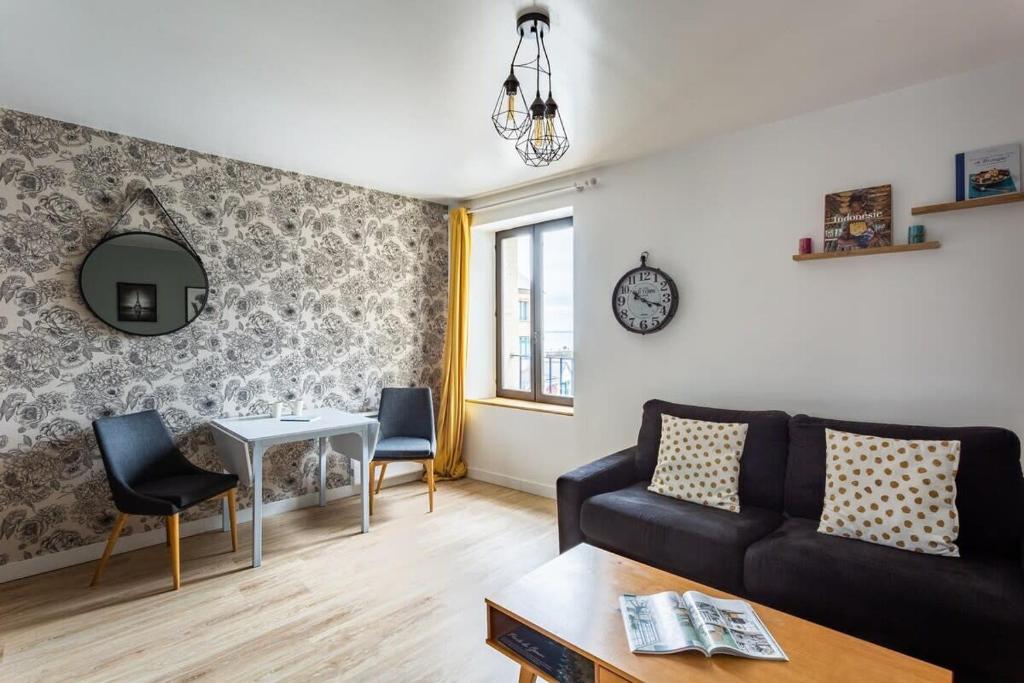 ein Wohnzimmer mit einem Sofa und einem Tisch in der Unterkunft La Brise- Joli T2 rénové - Vue Mer - 1 chambre in Cancale