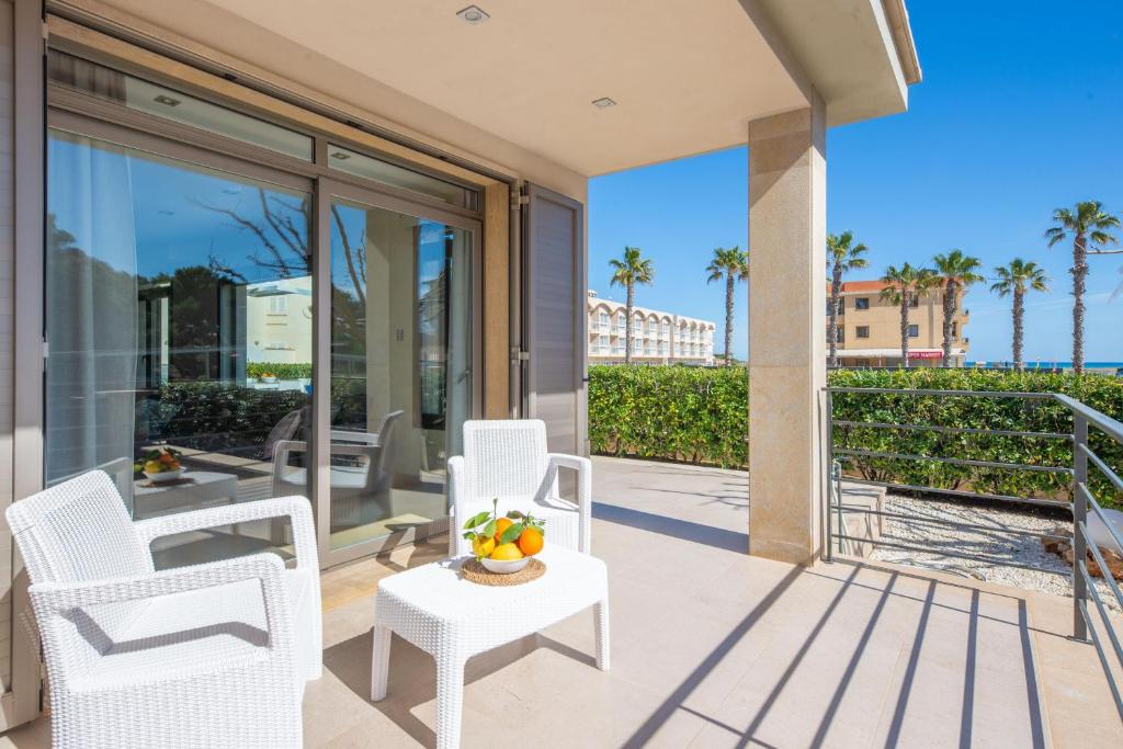 un balcone con sedie bianche e un tavolo con frutta. di Antonia a Can Picafort