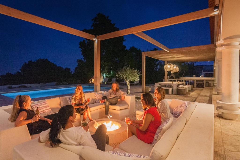 a group of people sitting around a fire pit at Tiny Whale Lodge, a unique space for groups in Bensafrim