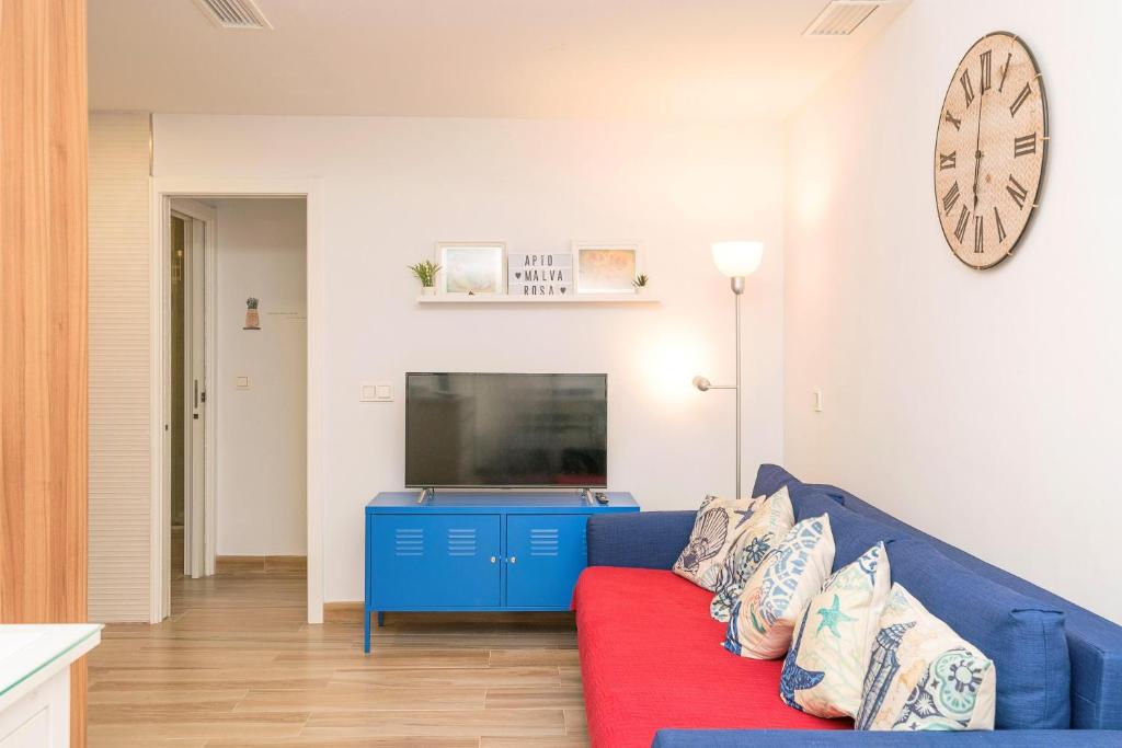 een woonkamer met een blauwe bank en een tv bij Loving Rota in Rota
