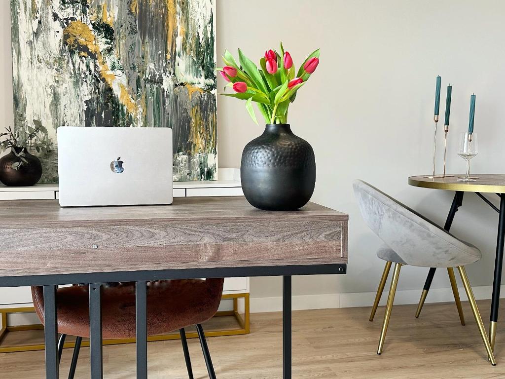 a table with a black vase with flowers on it at Neu & Schick: Küche inkl. Kaffee in Dresden