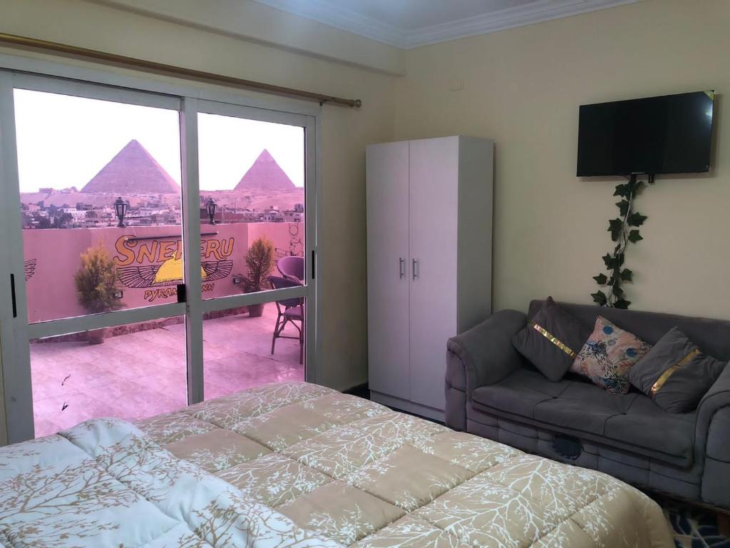 a bedroom with a bed and a view of the pyramids at Sneferu Pyramids inn - Full Pyramids View in Cairo