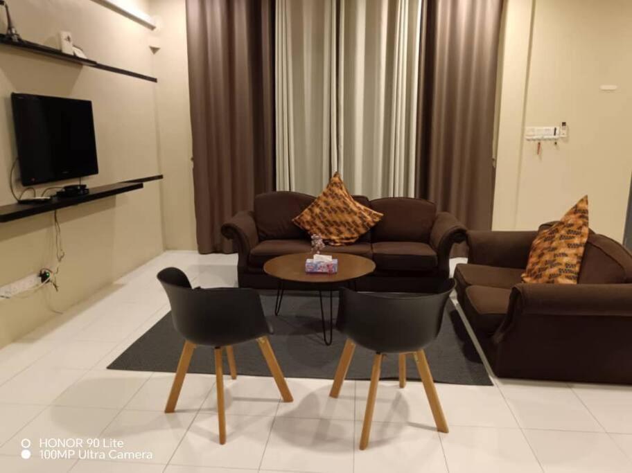 uma sala de estar com um sofá, uma mesa e cadeiras em Homestay Alamanda em Kuching