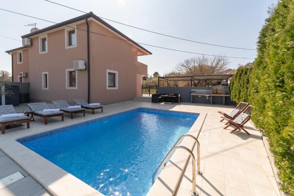 a swimming pool with chairs and a house at Holiday Home Kiara in Brtonigla