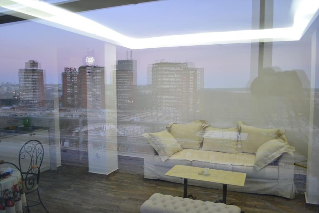 sala de estar con sofá frente a una ventana en Rooftop New Belgrade Apartment, en Belgrado