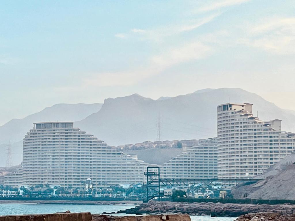two large hotel buildings with mountains in the background at Pyramids Porto El Sokhna Familis Only in Ain Sokhna