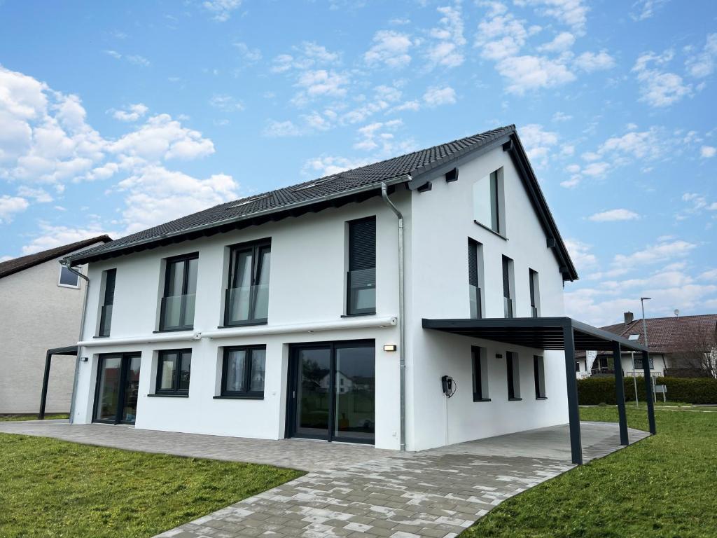 een wit huis met een zwart dak bij Wunderschöne DHH am Tor zum Allgäu in Primisweiler
