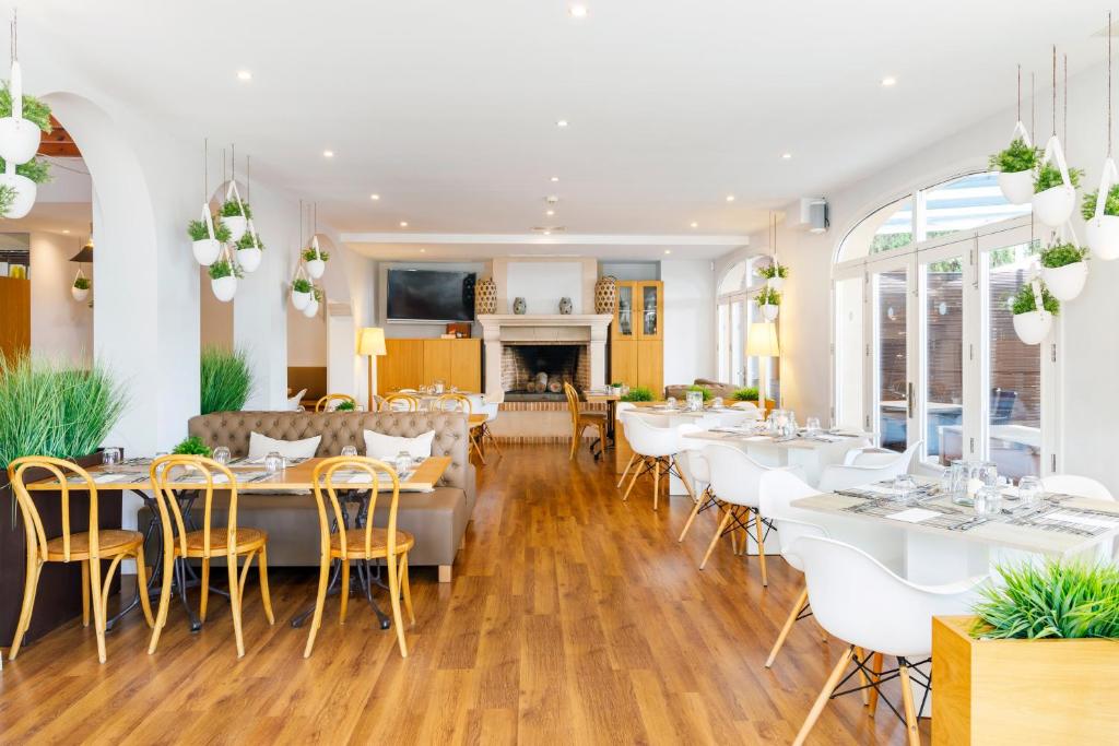 a restaurant with tables and chairs and a fireplace at Mar Hotels Alcanada in Port d'Alcudia
