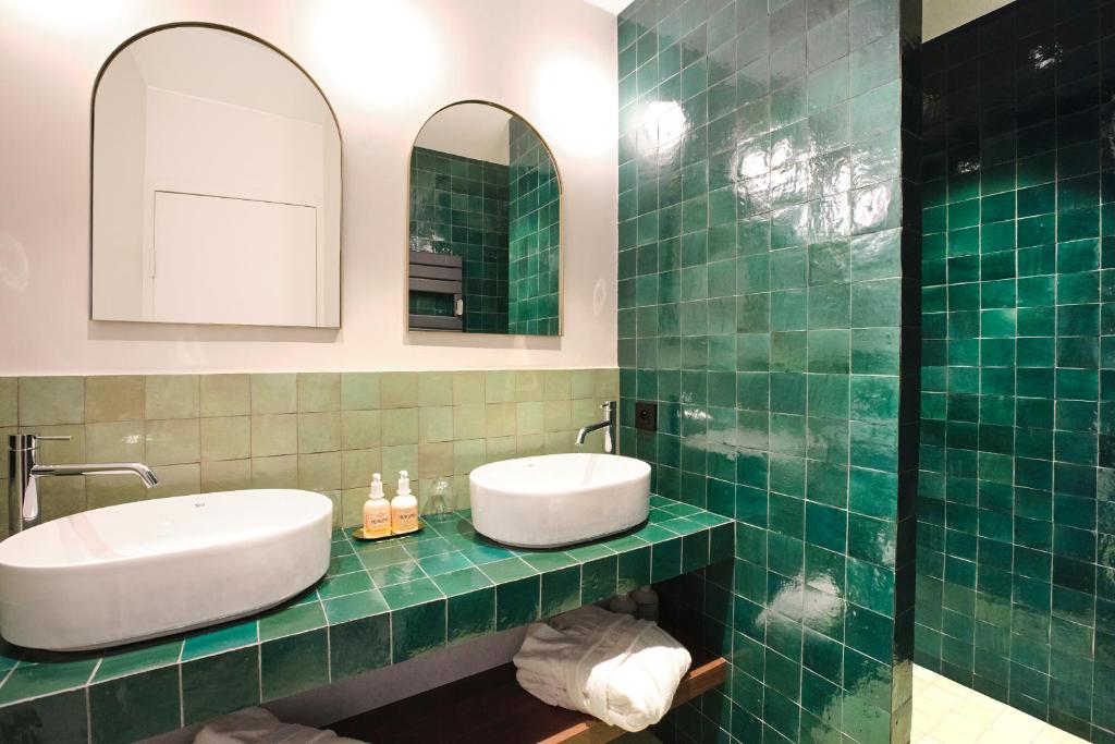 a green tiled bathroom with a sink and a mirror at Maison Heym Bordeaux in Bordeaux
