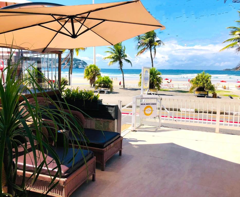 um banco com um guarda-sol na praia em Costa Maris Beach Hotel Frente Mar no Guarujá